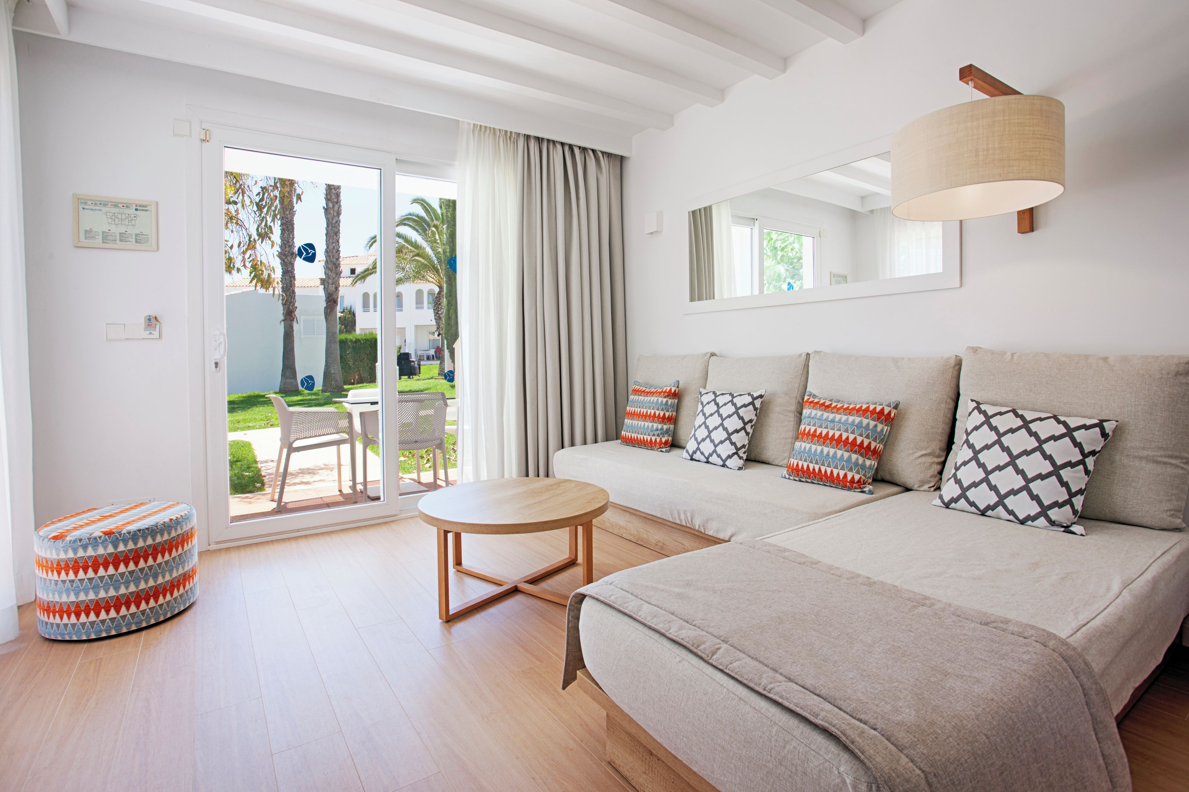 A modern living room with a sofa, a round coffee table, and a patterned ottoman.