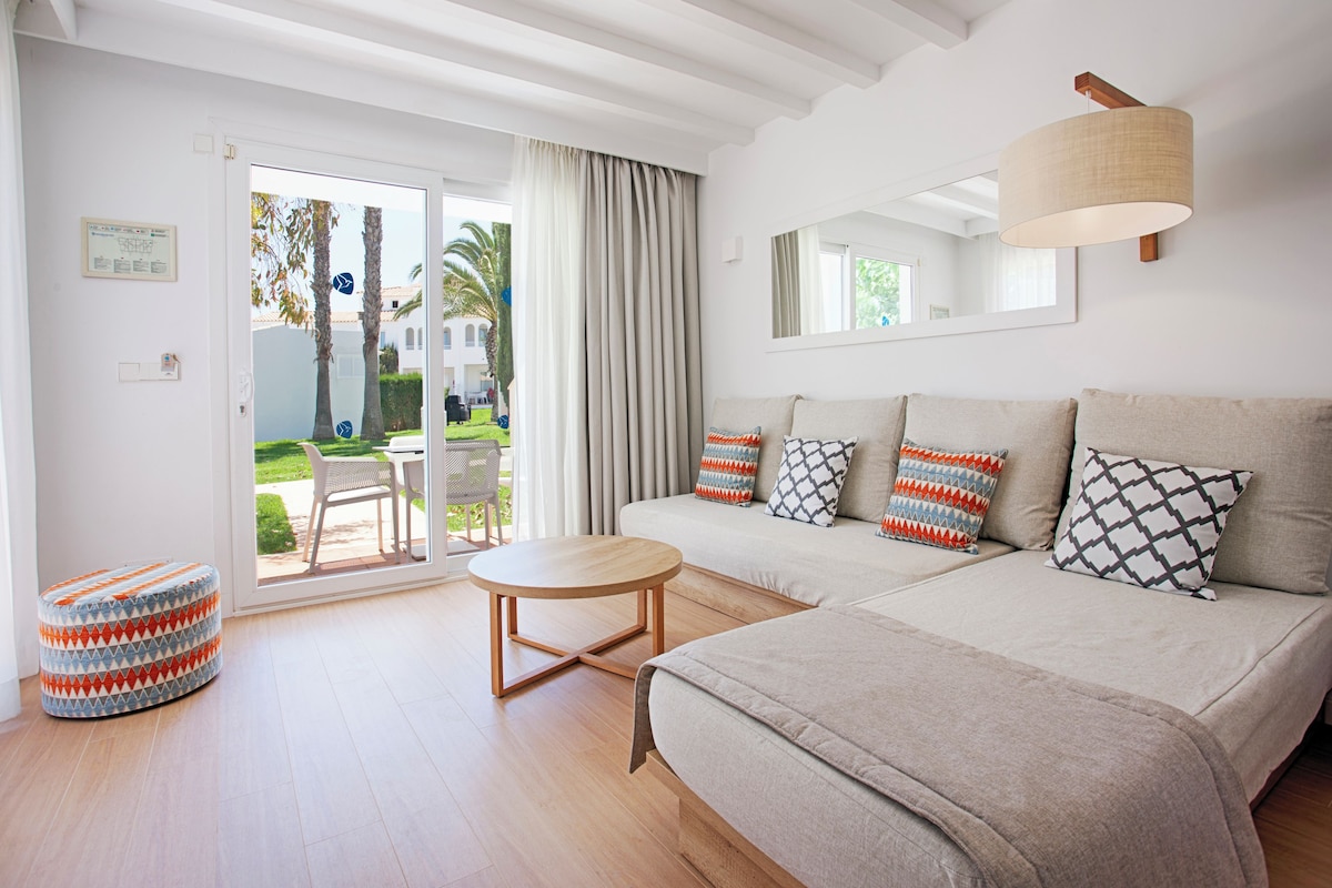 A modern living room with a sofa, ottoman, and round table.