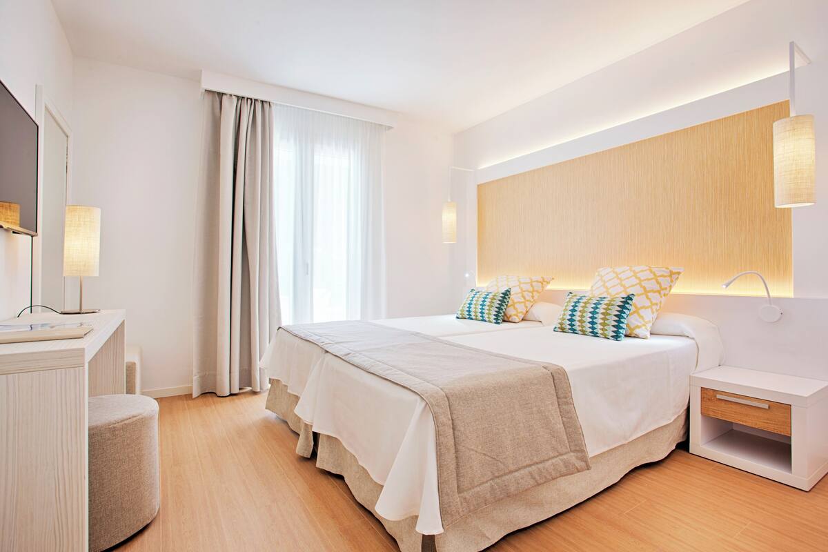 Une chambre à coucher moderne avec un grand lit, des tables de chevet, une commode, un miroir et une fenêtre avec des rideaux.