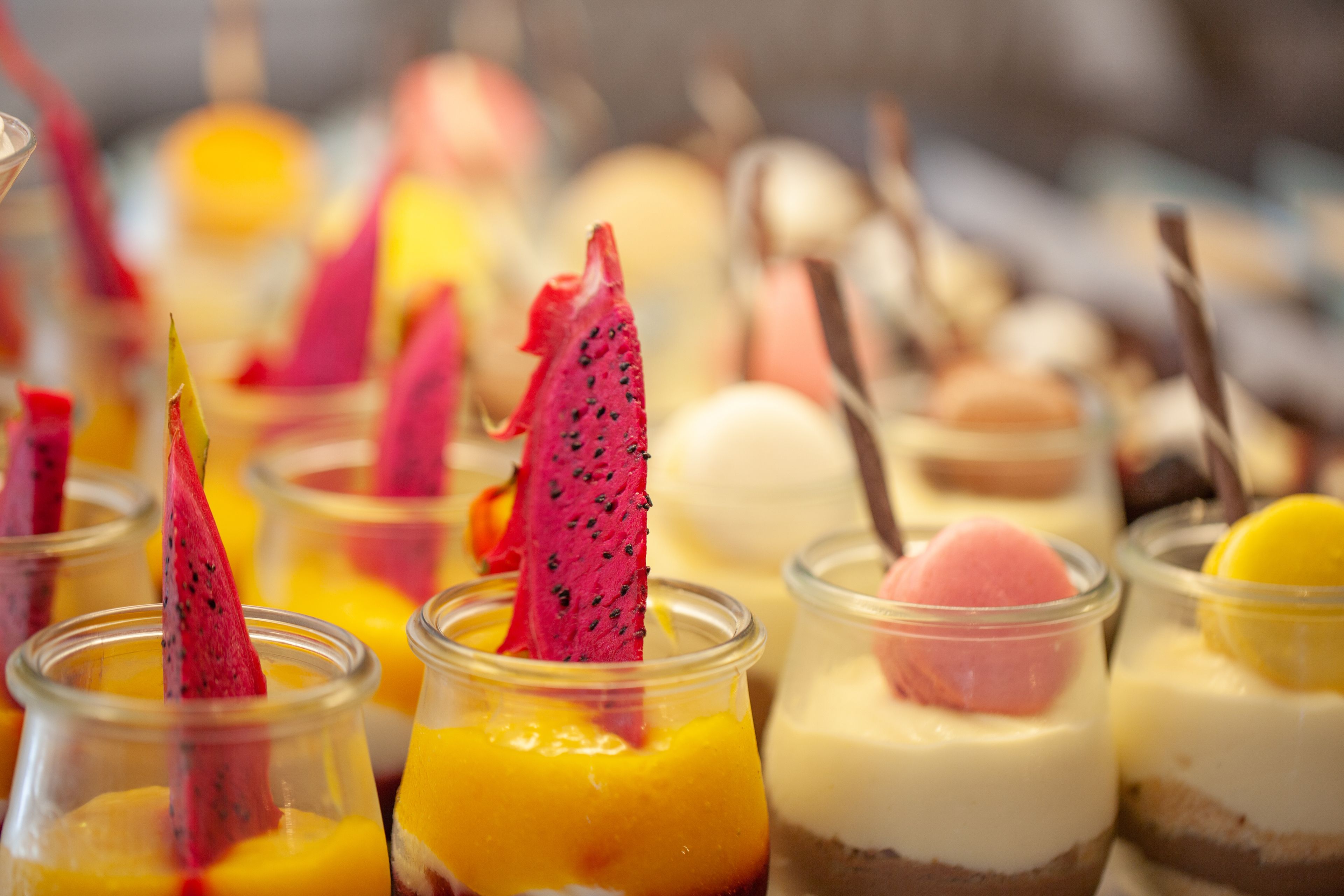 Diverses postres a copes transparents, com ara mango, fruit de drac i xocolata.