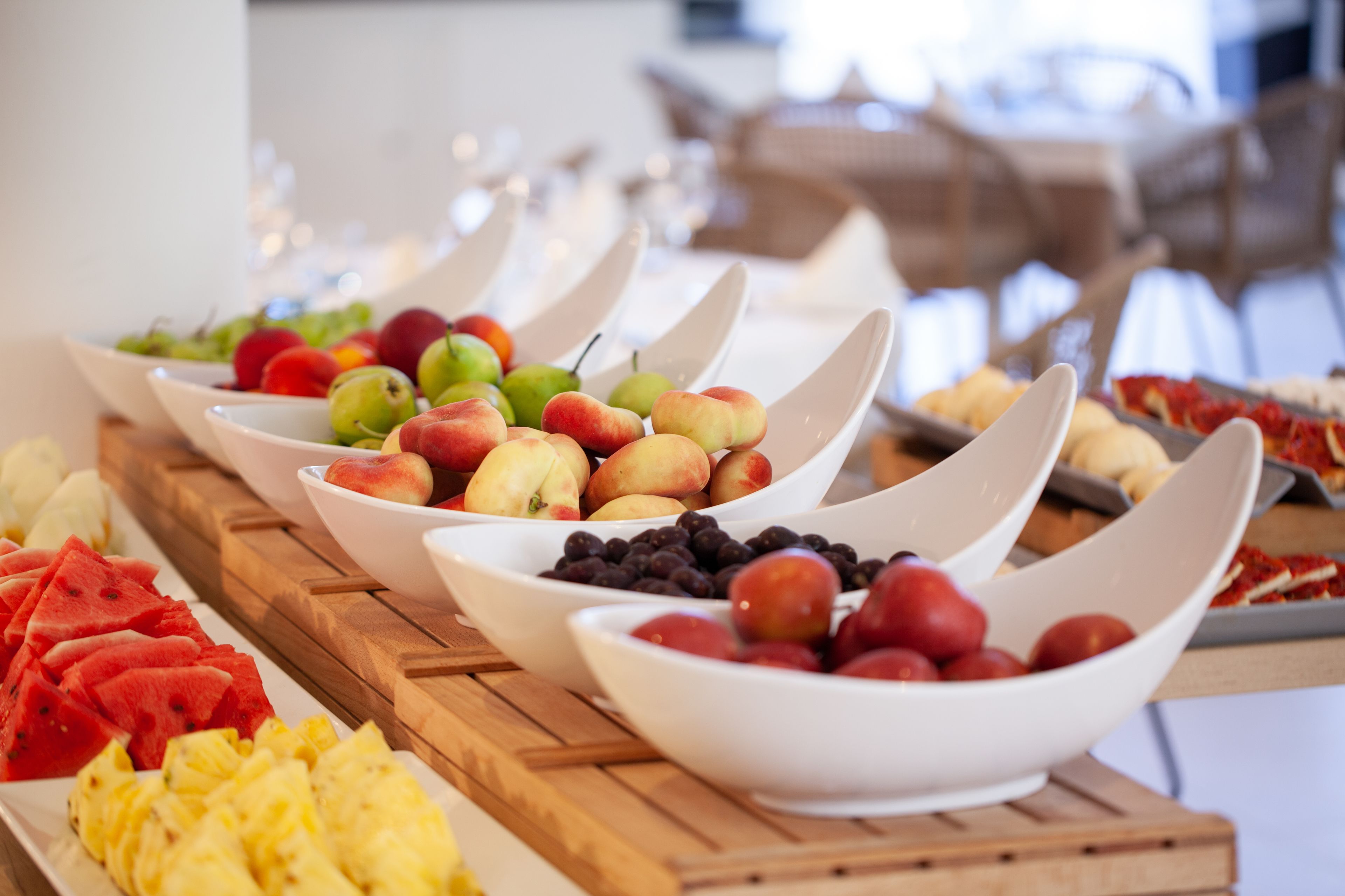 A buffet with various fruits and pastries arranged on a wooden table.