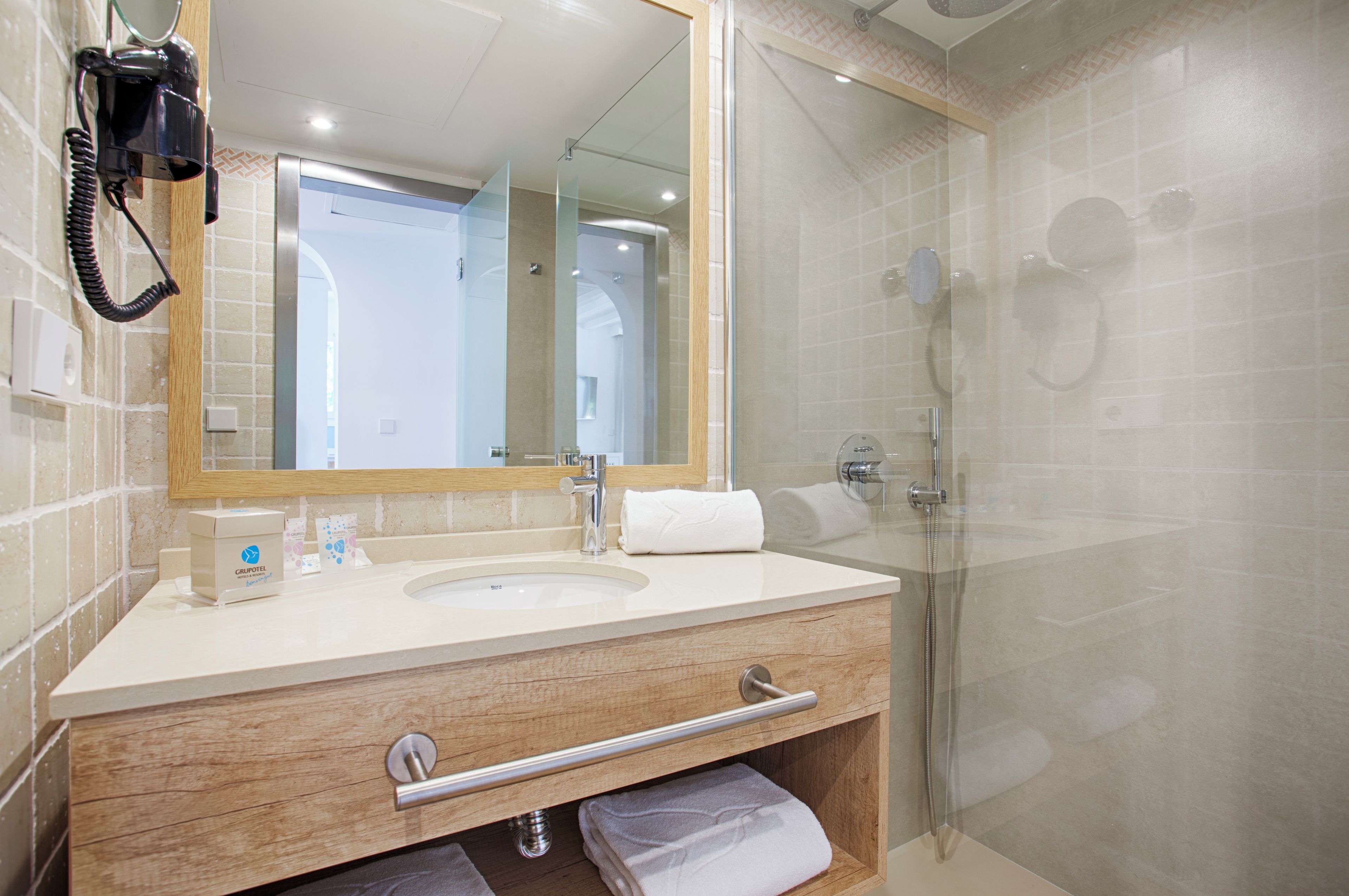 A bathroom with a sink, mirror, and shower.