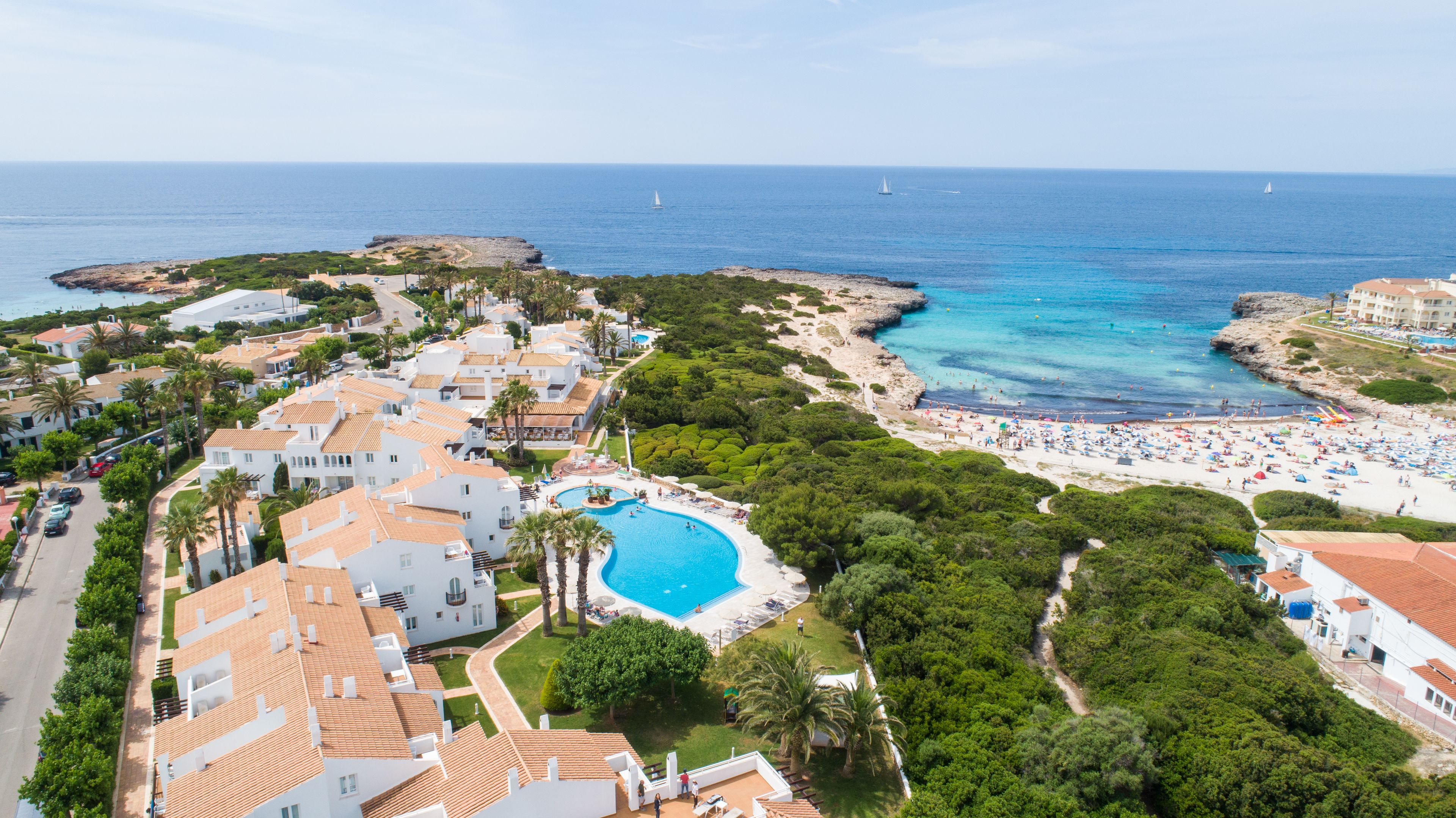 Un complejo turístico frente al mar con piscina, playa y vistas al océano.