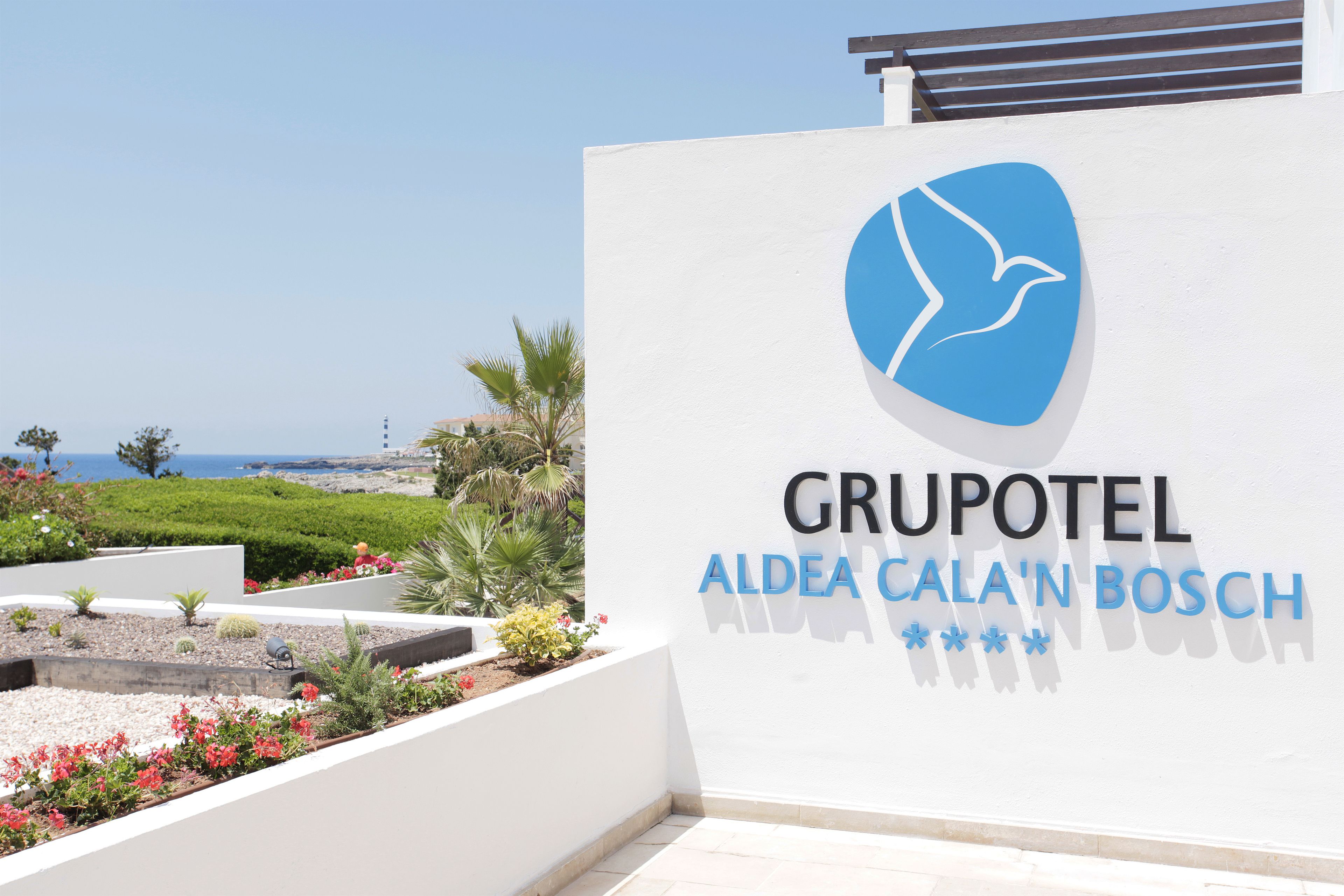 A hotel sign with a logo and name 'GRUPOTEL ALEDA CALA'N BOSCH'.
