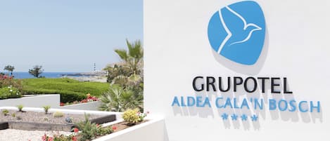 A hotel sign with a logo and name 'GRUPOTEL ALEDA CALA'N BOSCH'.