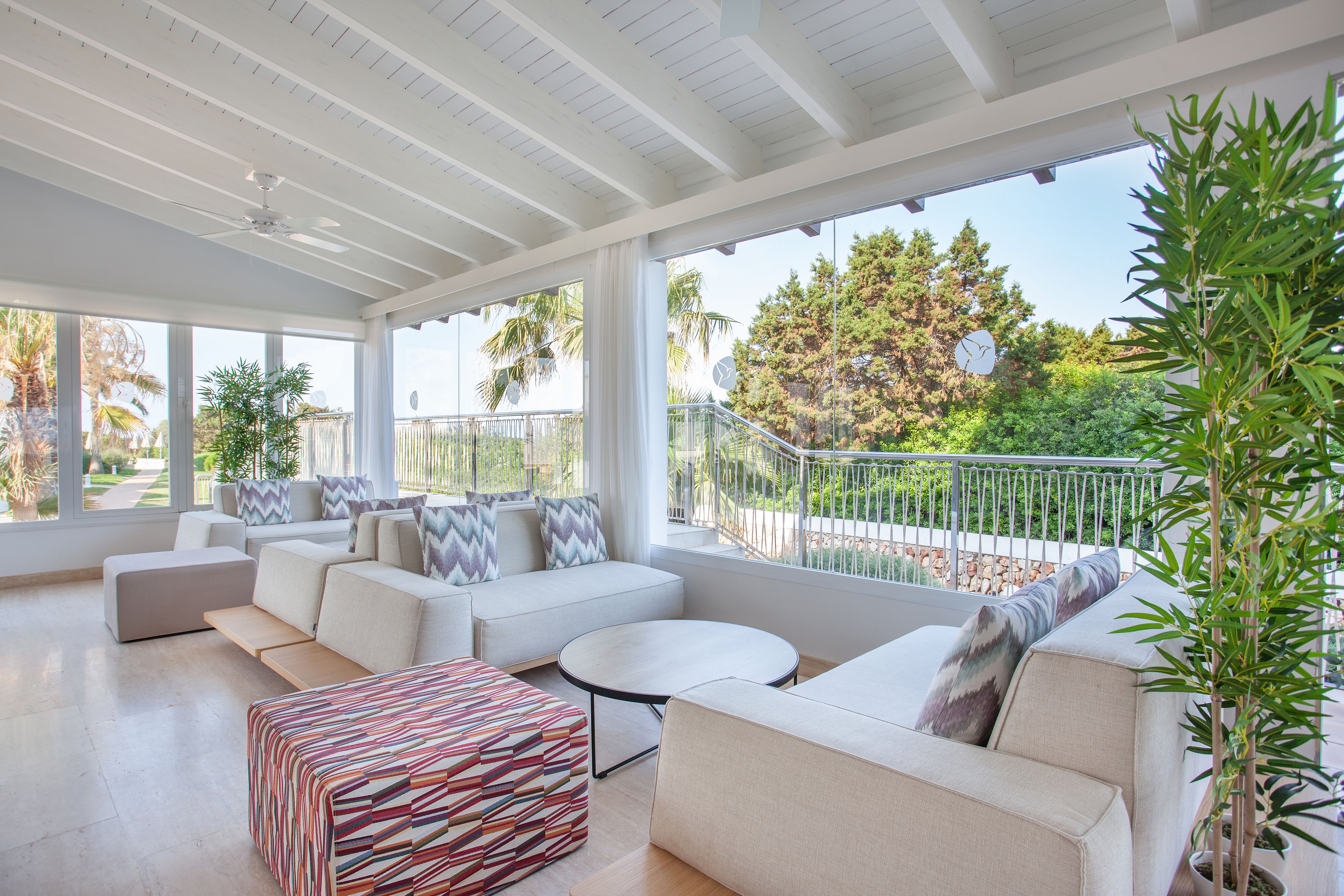 A spacious living area with a large window, a ceiling fan, and a potted plant.