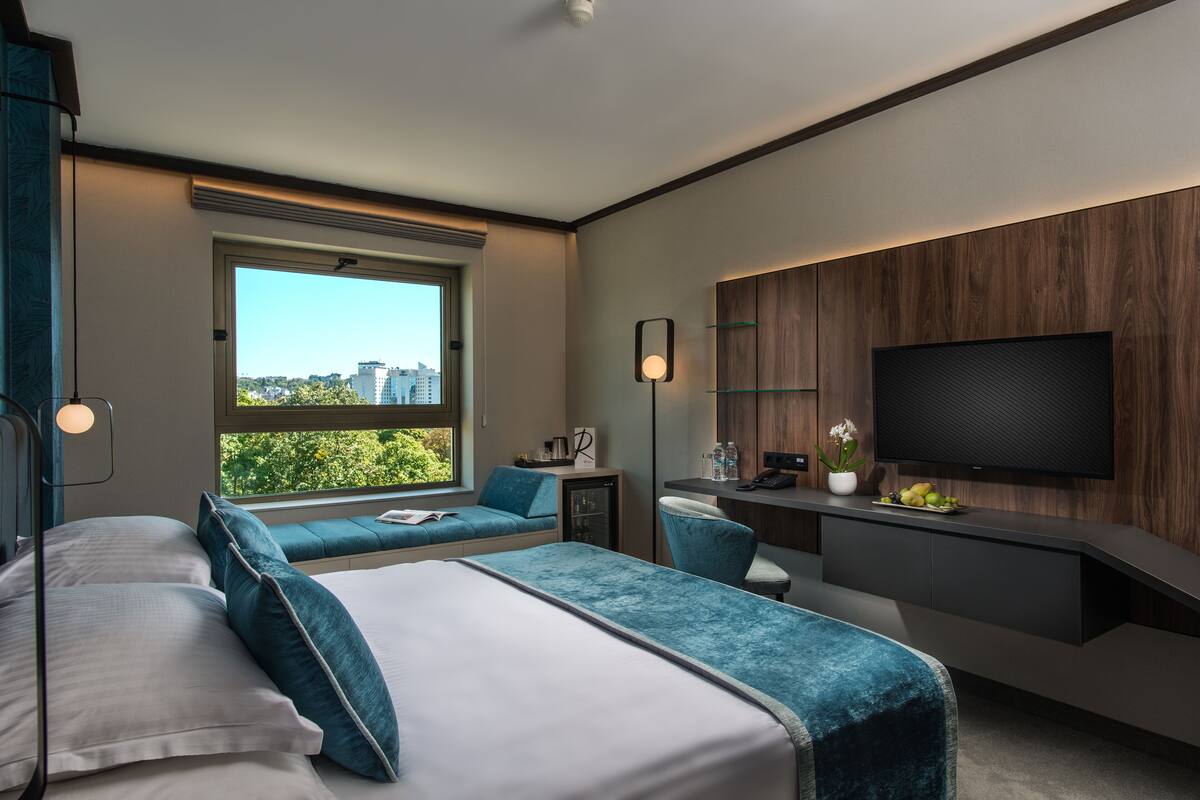 A modern hotel room with a large bed, a desk, and a TV.