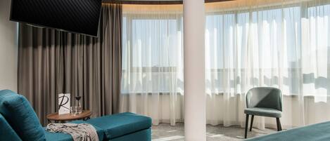 Una habitación de hotel moderna con una televisión de pantalla plana grande, un sofá, una silla y una cama.