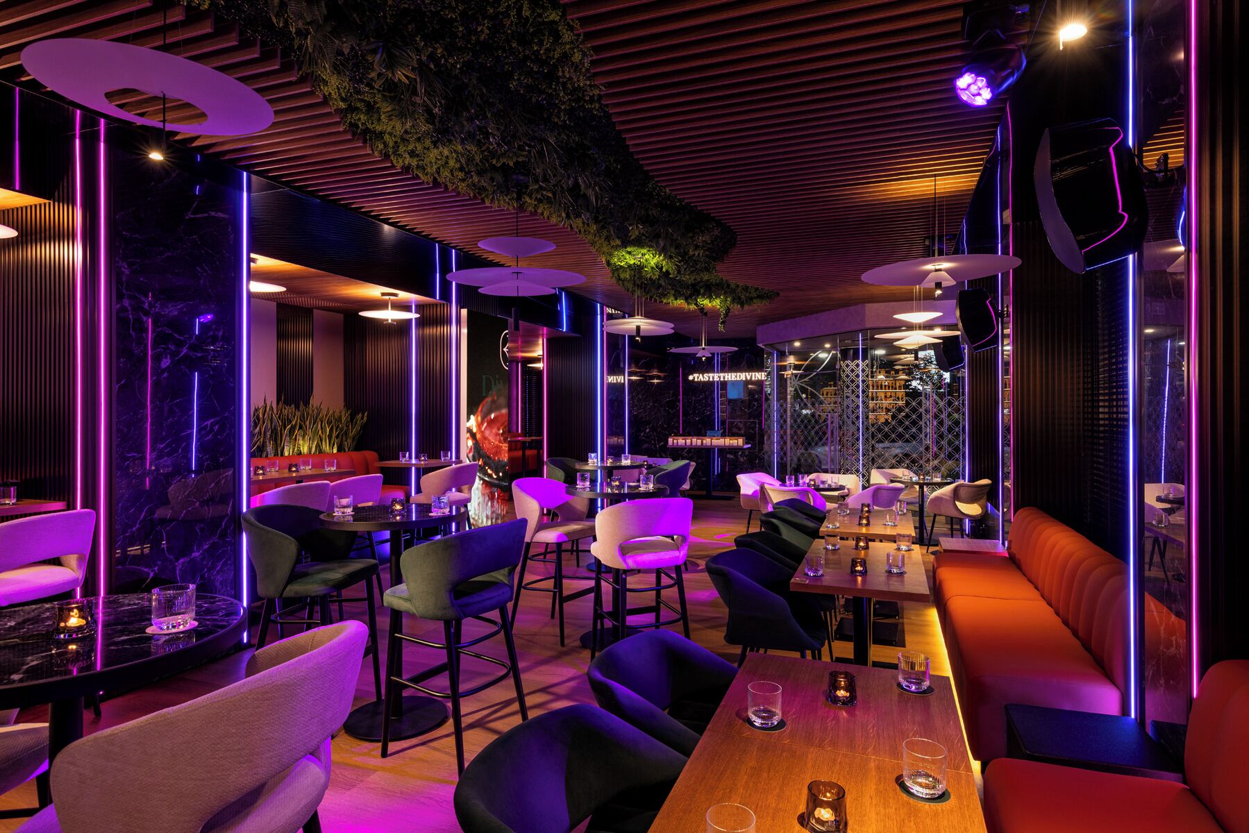 A modern restaurant interior with round tables, cushioned seating, and ambient lighting.