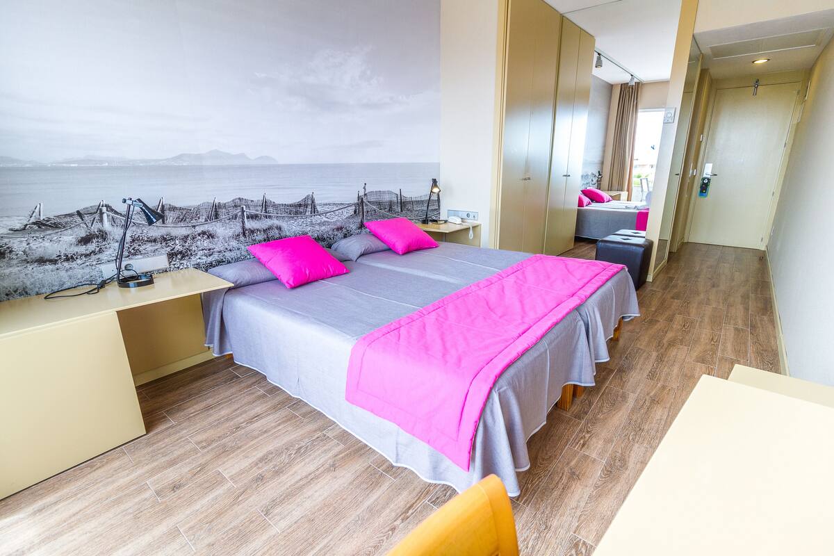 Habitación de hotel moderna con una cama grande, un escritorio y vistas al mar.