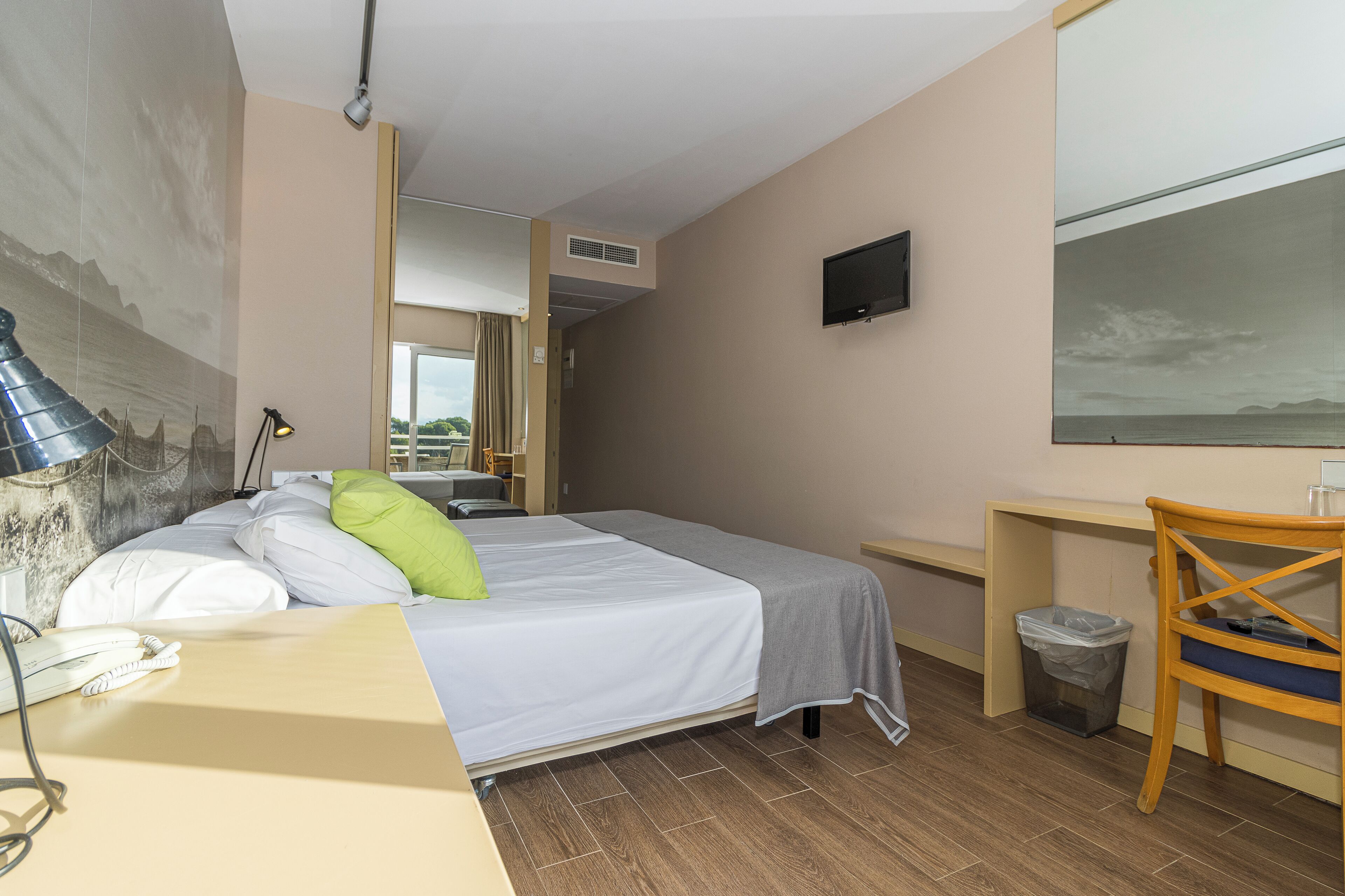 Une chambre d’hôtel avec un lit, un bureau, une chaise, une télévision et un tableau au mur.