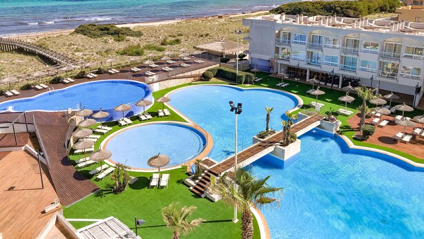 A resort with multiple swimming pools, a beach, and a mountain backdrop. - Eix Platja Daurada Hotel & Spa (Santa Margalida)