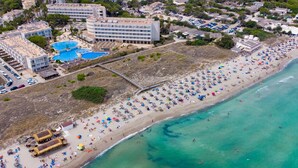 An aerial view of a coastal hotel with multiple swimming pools, a beach with numerous umbrellas, and a clear turquoise sea. - Eix Platja Daurada Hotel & Spa (Santa Margalida)
