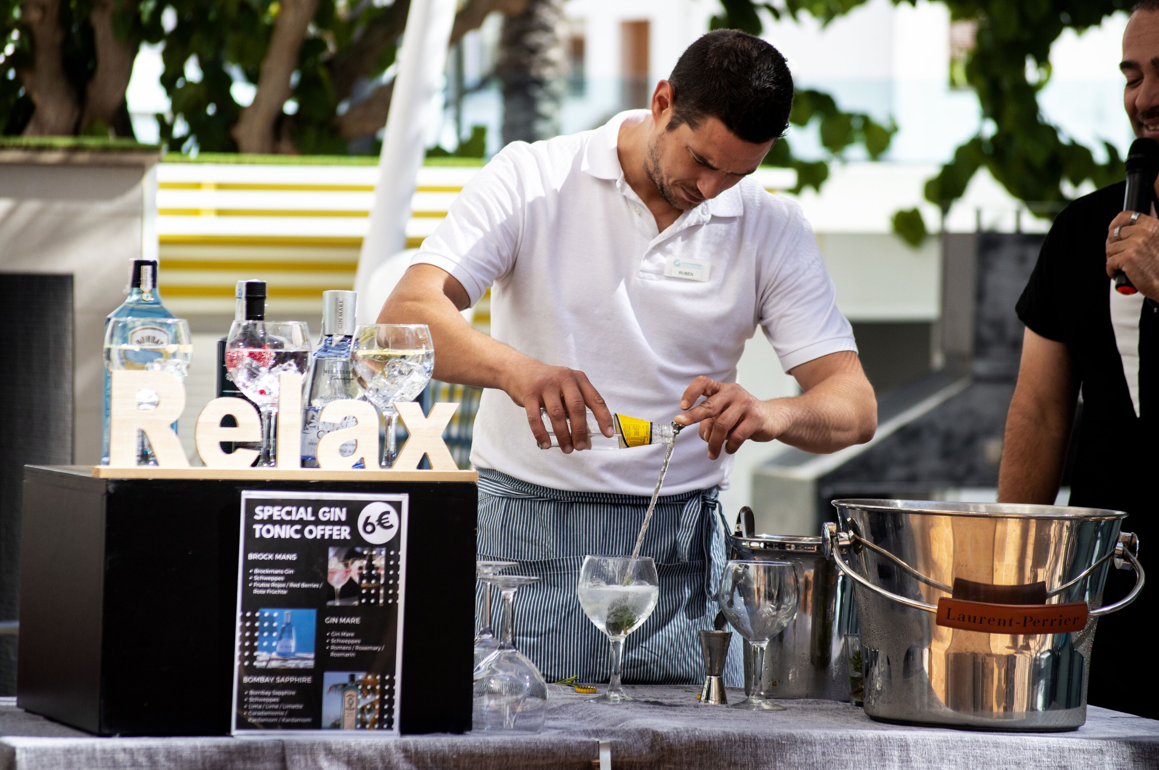 A bar area with a 'Relax' sign, a 'Special Gin Tonic Offer' sign, and a bartender pouring a drink.