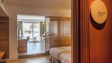 A hotel room with a wooden door, a number plate '507', a bed, a desk, and a view of the outside.