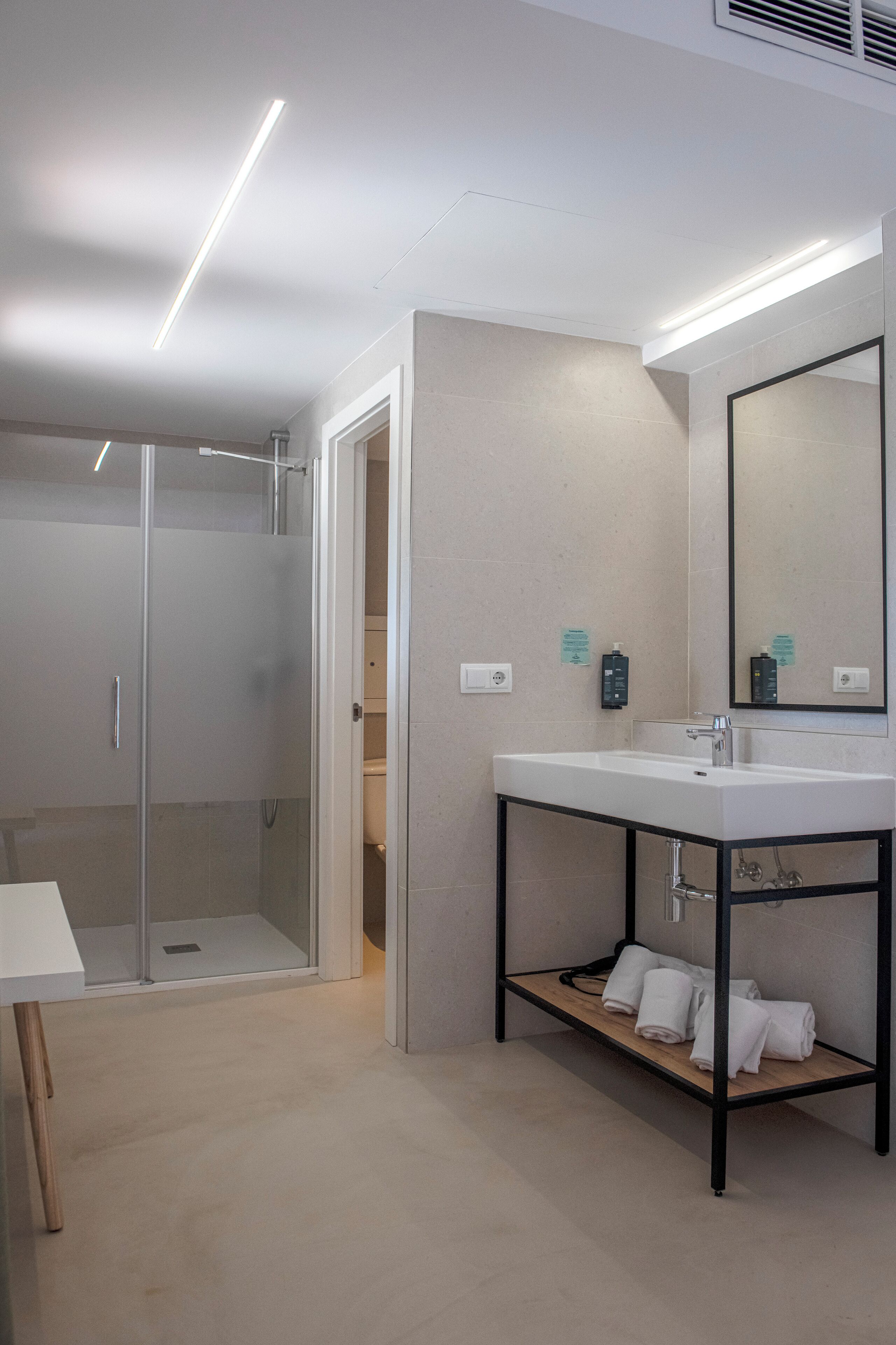 Une salle de bain moderne avec une douche à parois de verre, un lavabo blanc doté d’un cadre noir et un miroir placé au-dessus.