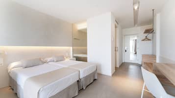 A modern hotel room with two beds, a wooden desk, and a mirror.