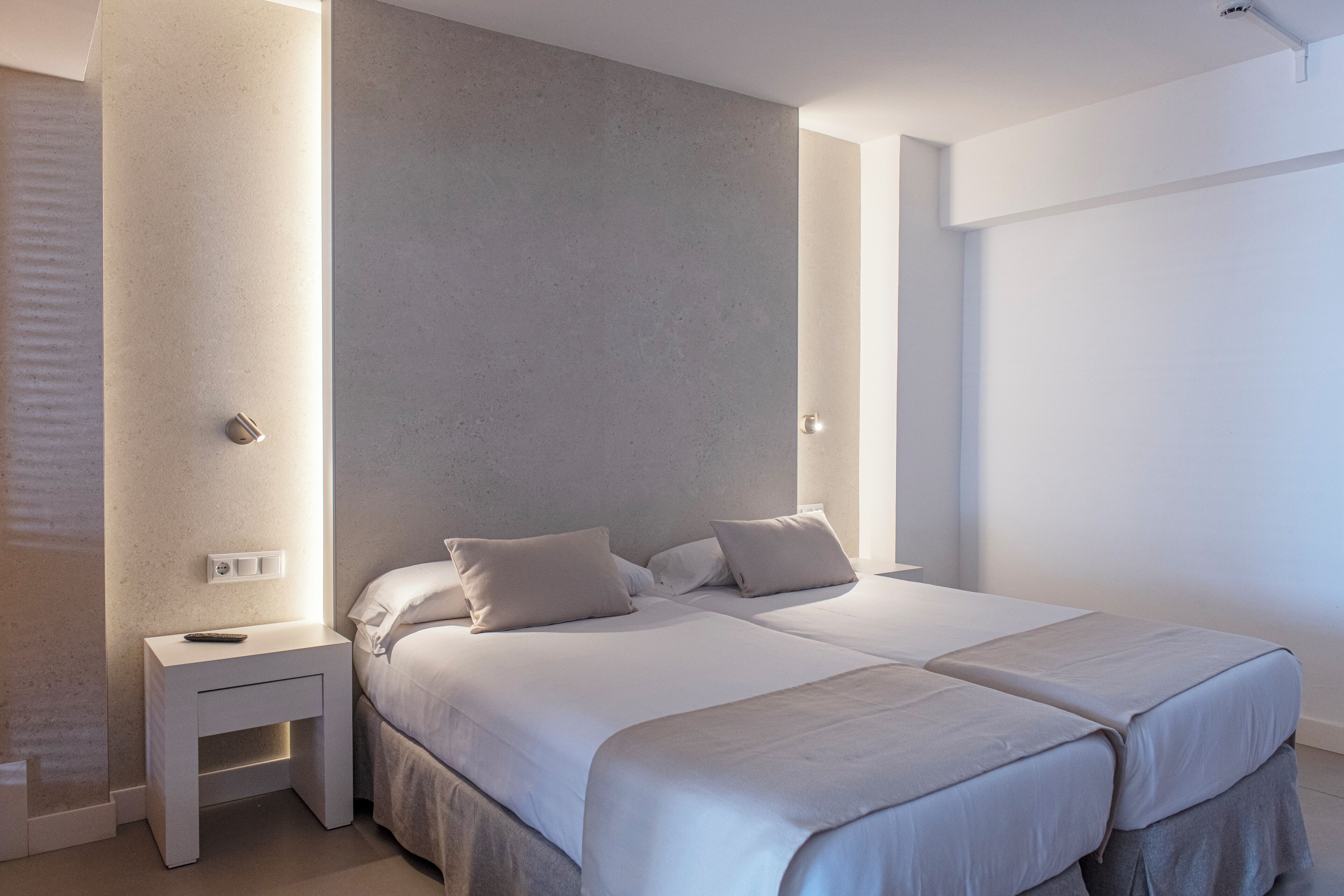 Une chambre moderne avec un grand lit, des tables de chevet et une palette de couleurs neutres.
