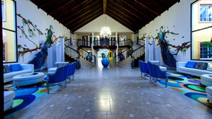 A spacious lobby with a high ceiling, a chandelier, and a central staircase. - Hotel Palma Real (Jutiapa)
