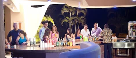 A bar area with a counter, seating, and a backdrop of palm trees.
