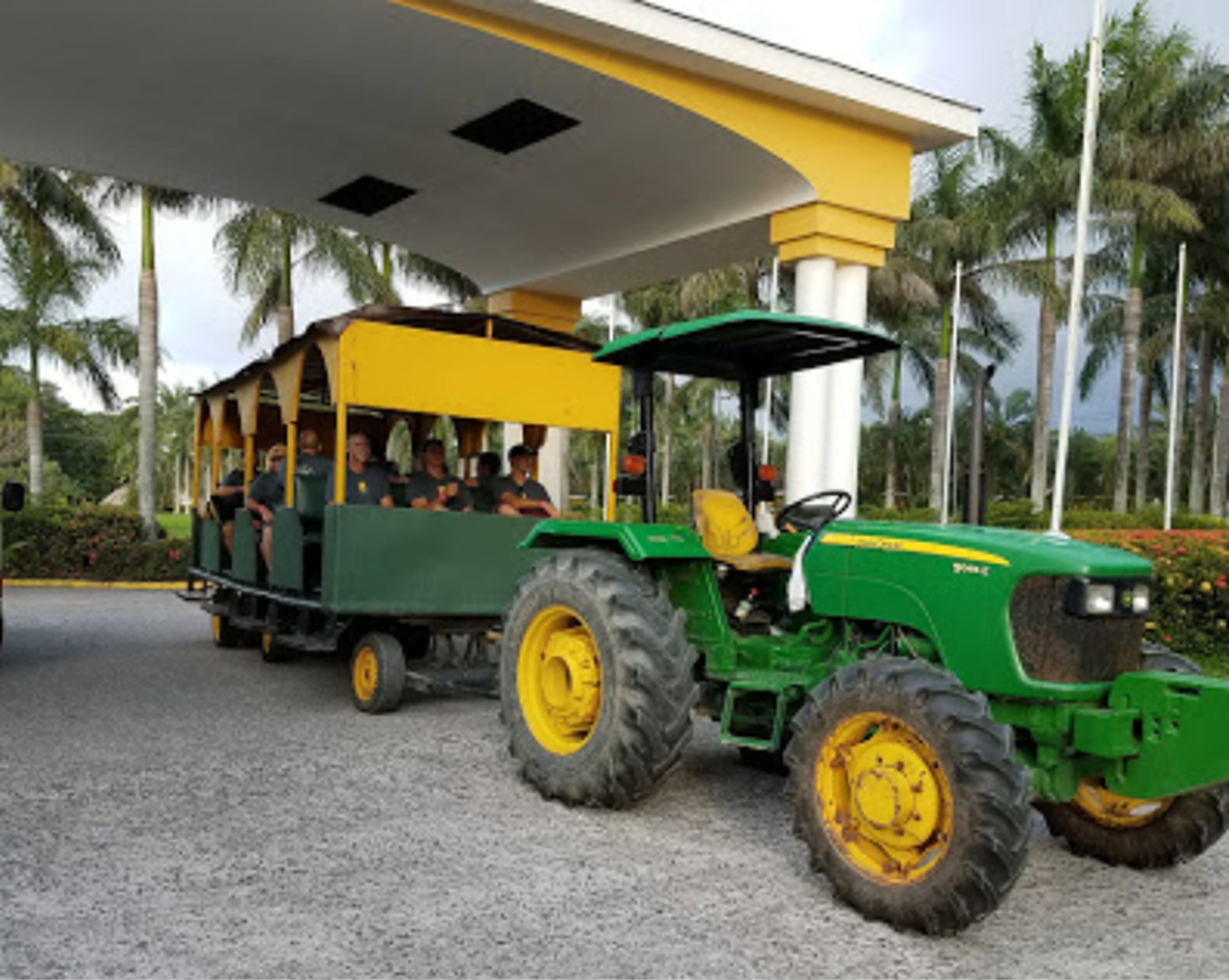 Ein grüner Traktor zieht ein gelb-grünes Personenfahrzeug.