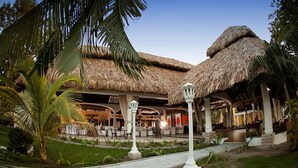 A resort with thatched-roof structures, outdoor seating, and a well-maintained garden. - Hotel Palma Real (Jutiapa)