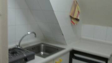 Uma cozinha pequena com pia, fogão e armários com puxadores amarelos.