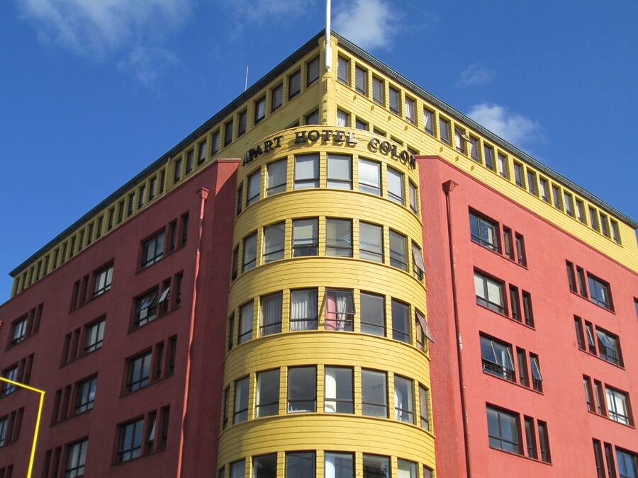 A corner building with a curved yellow facade and a red base.