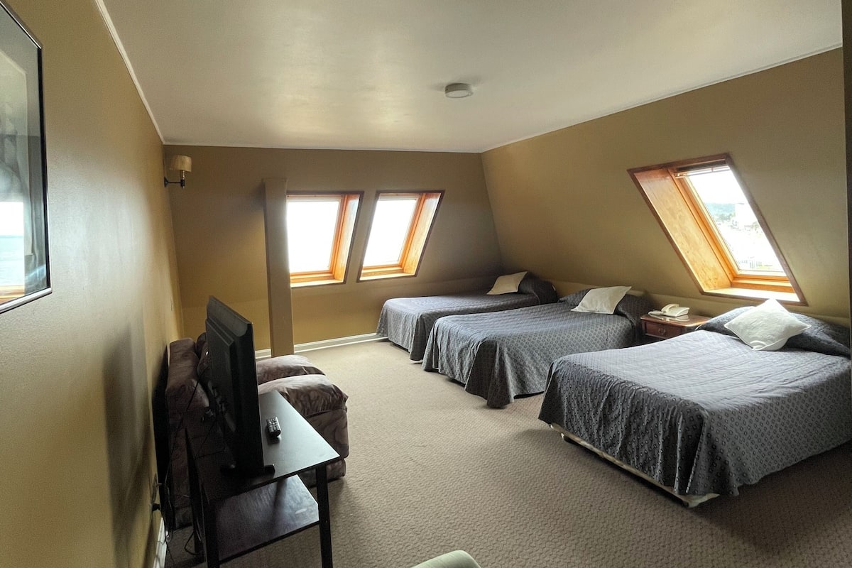 A room with two beds, a desk, a chair, and a television.