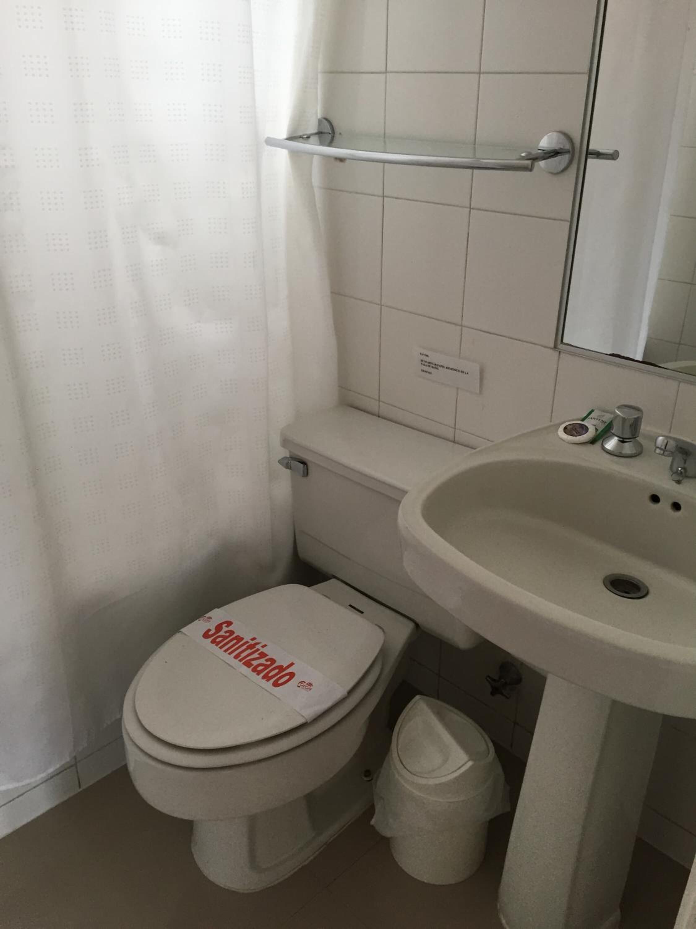 Un baño con inodoro, lavabo y cortina de ducha.