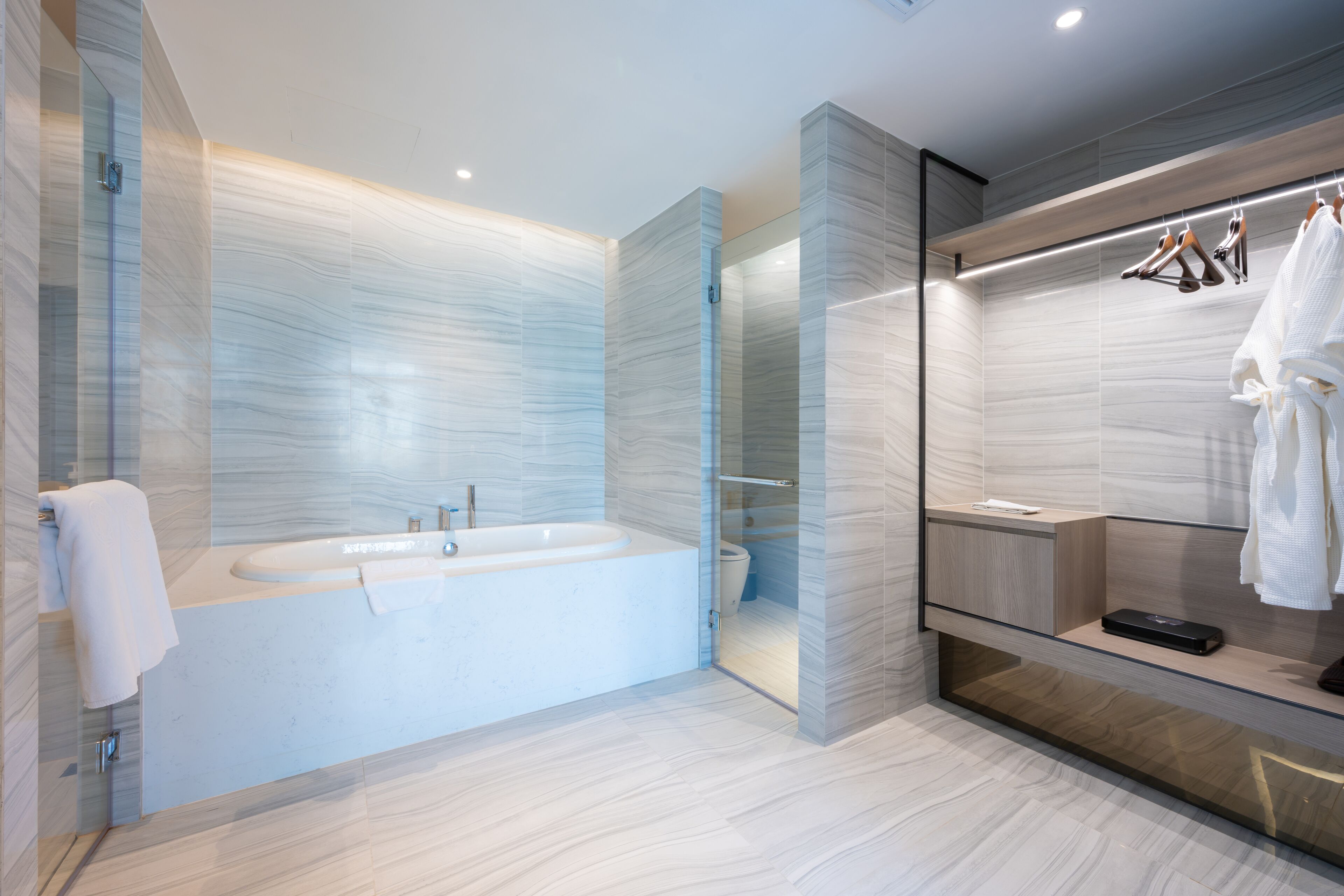 Un baño moderno con una bañera independiente, cabina de ducha con mampara de vidrio y tocador empotrado con espejo.