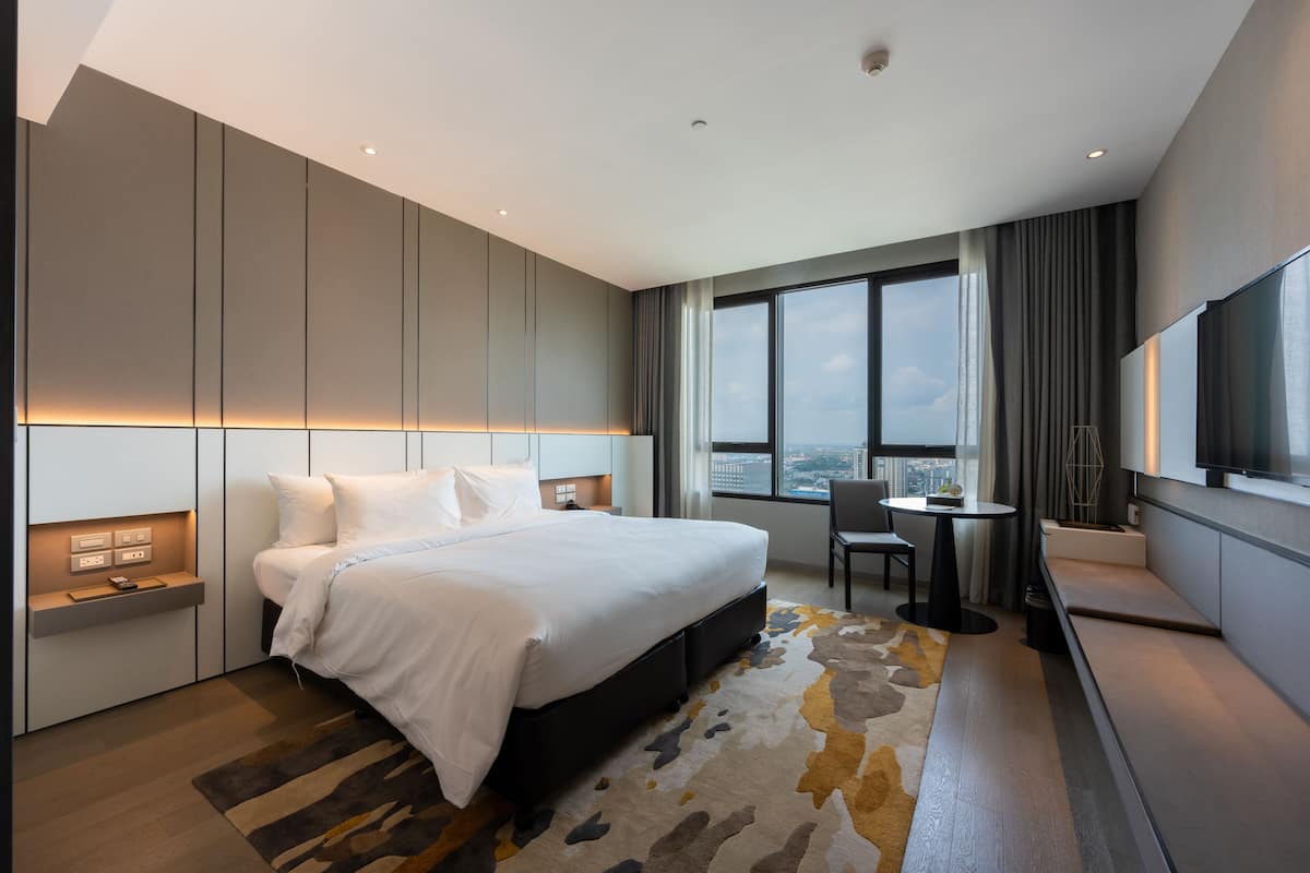 A modern hotel room with a large bed, a desk, and a TV.