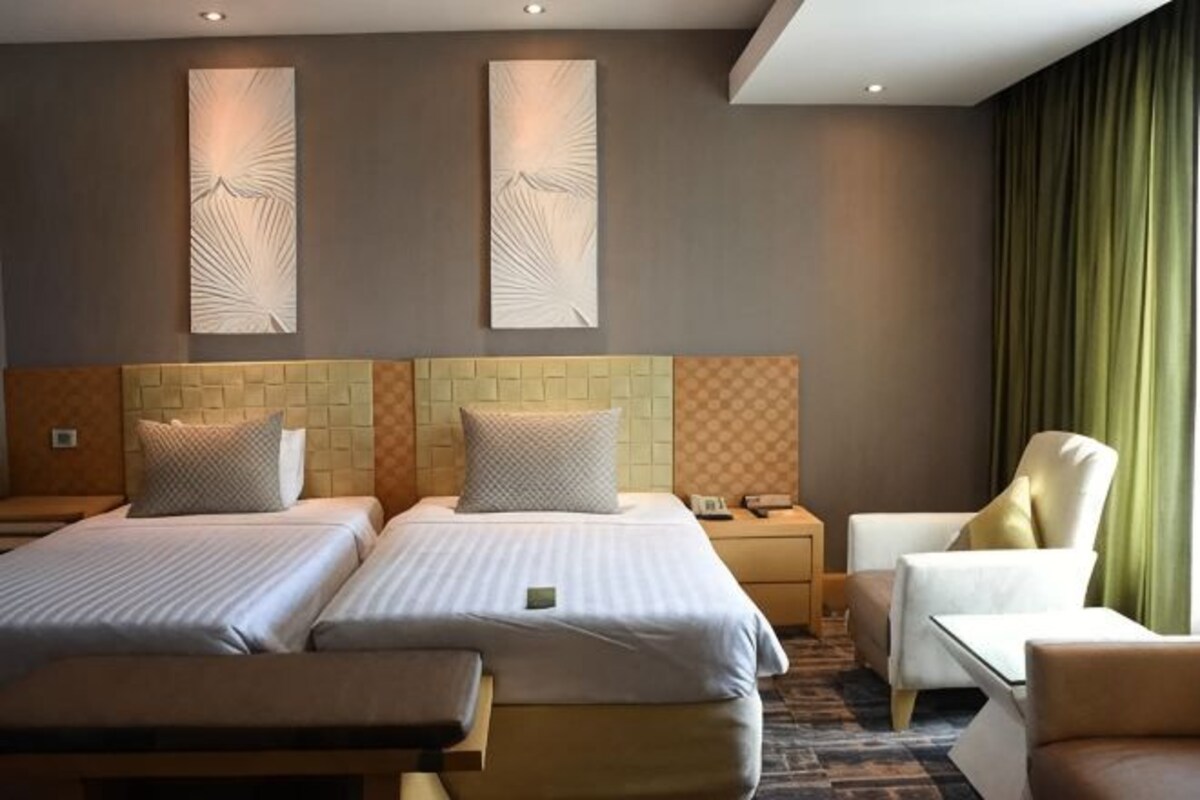 Een hotelkamer met twee bedden, een slaapbank, een fauteuil en een bureau.