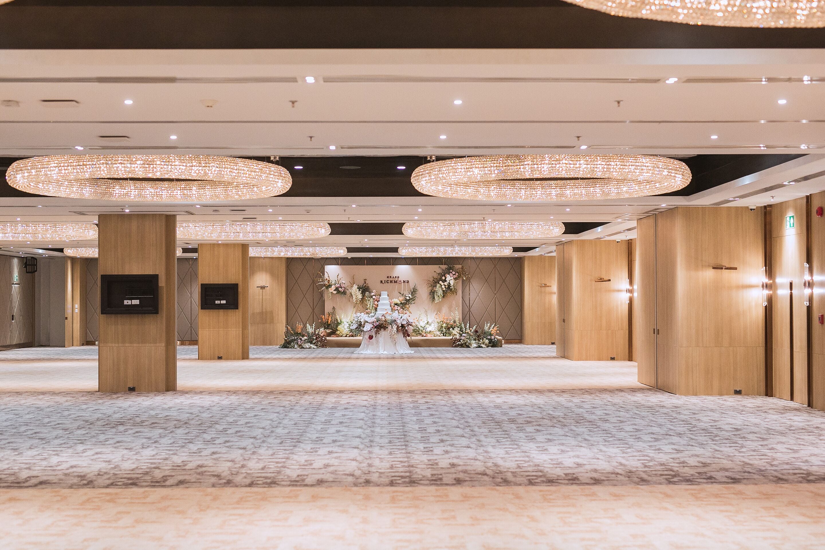 A spacious hotel lobby with a carpeted floor, wooden paneling, and a reception desk.