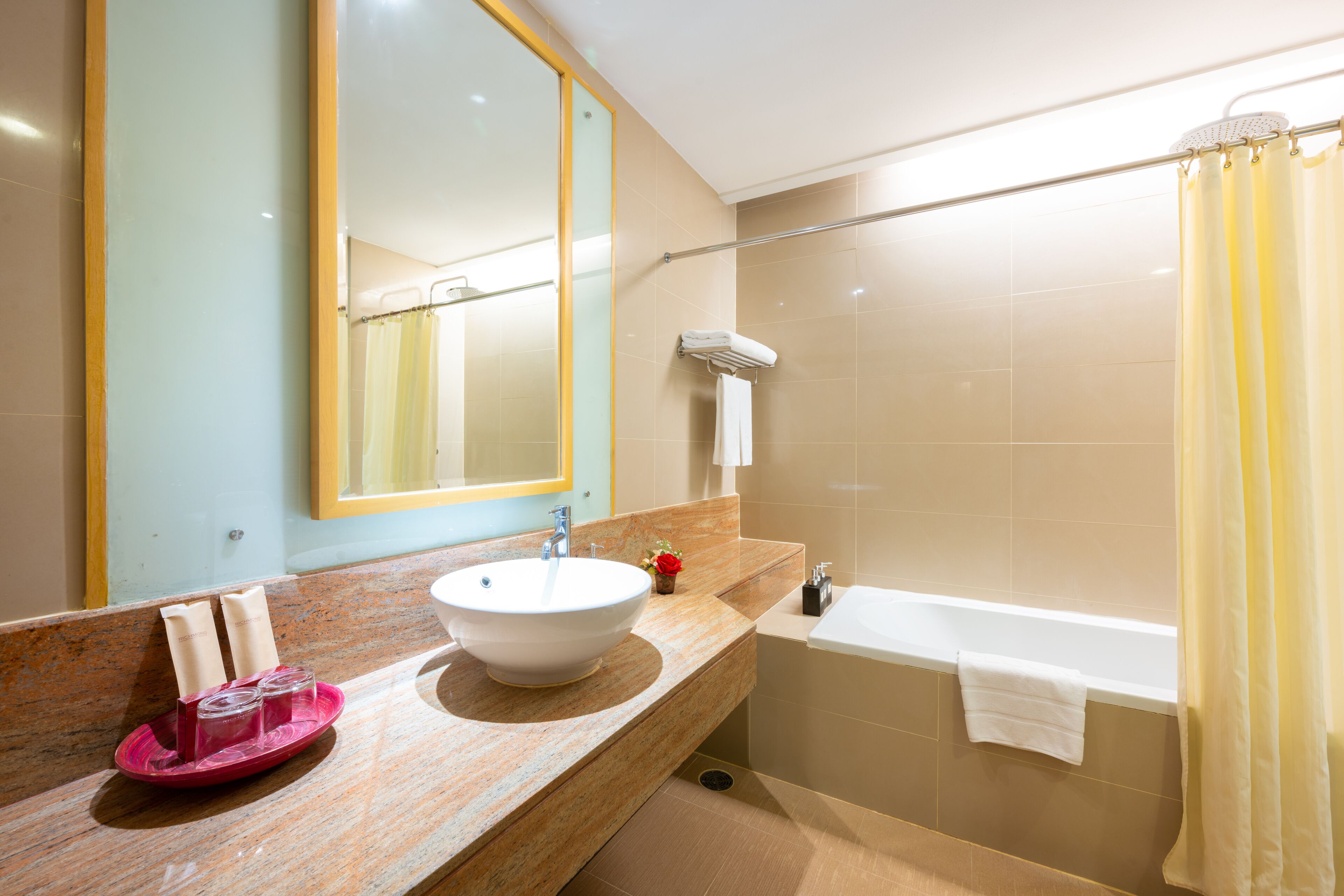 A bathroom with a sink, mirror, and bathtub.