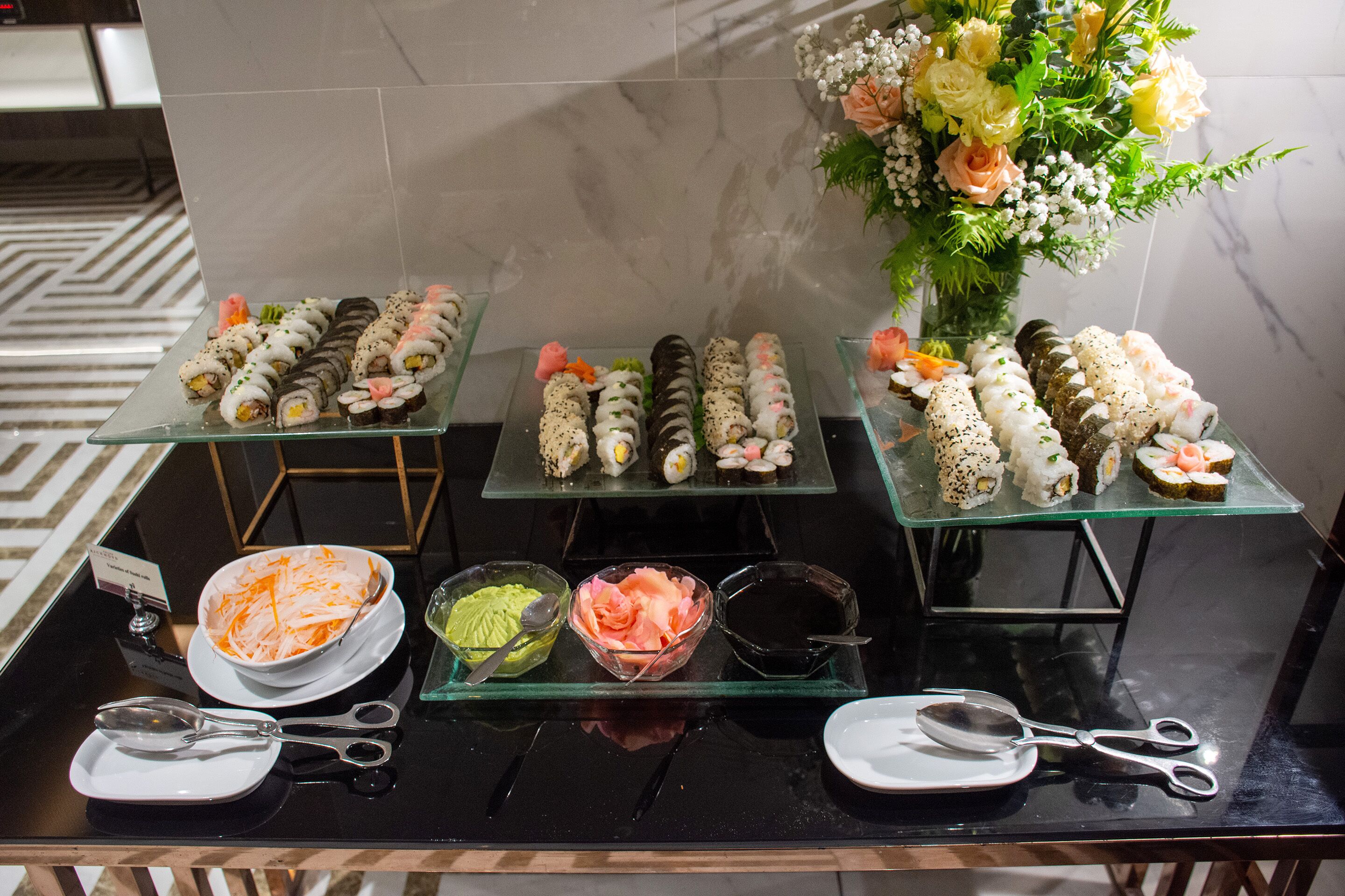 A buffet table with various sushi rolls and condiments.