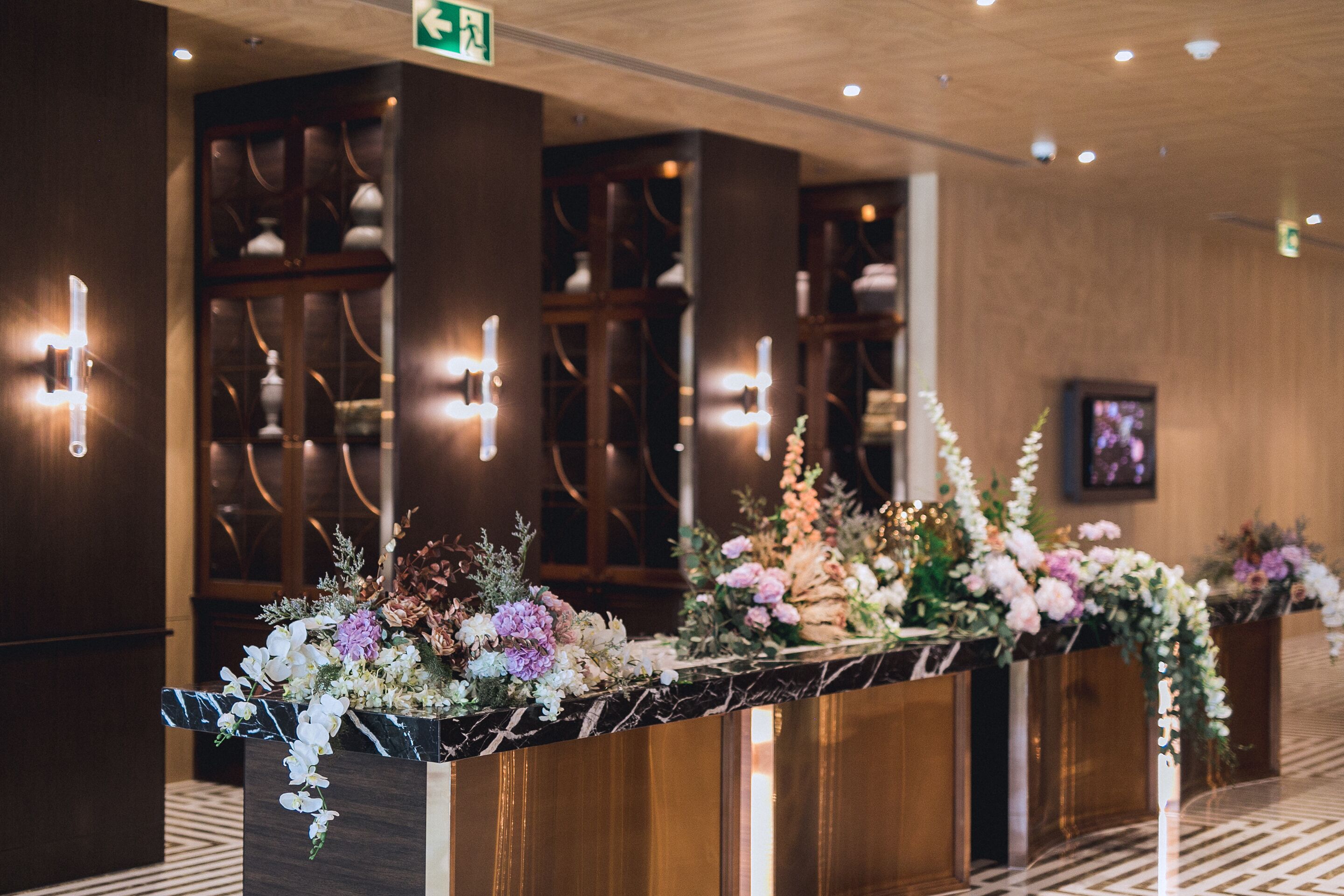 A reception area with marble counters and floral arrangements.
