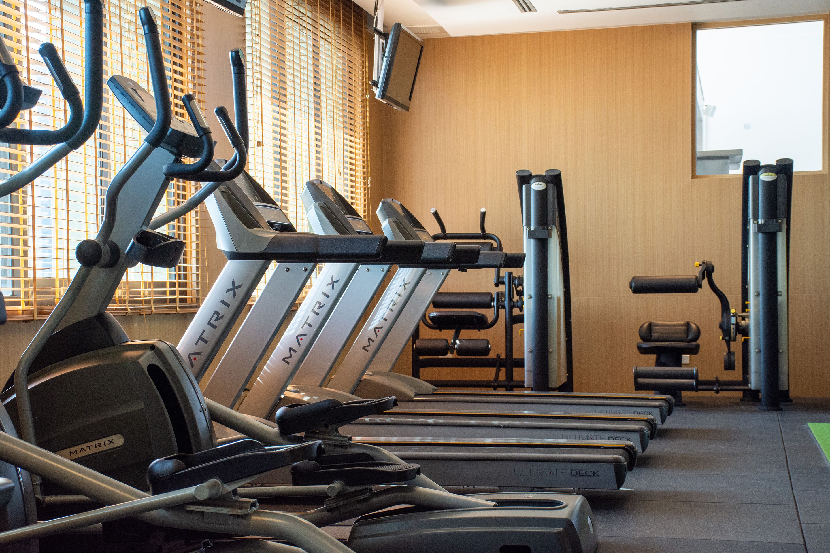 A gym with multiple treadmills, weight machines, and a television mounted on the wall.