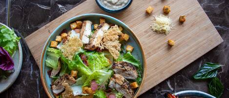 Ensalada con crutones y queso rallado sobre una tabla de madera.