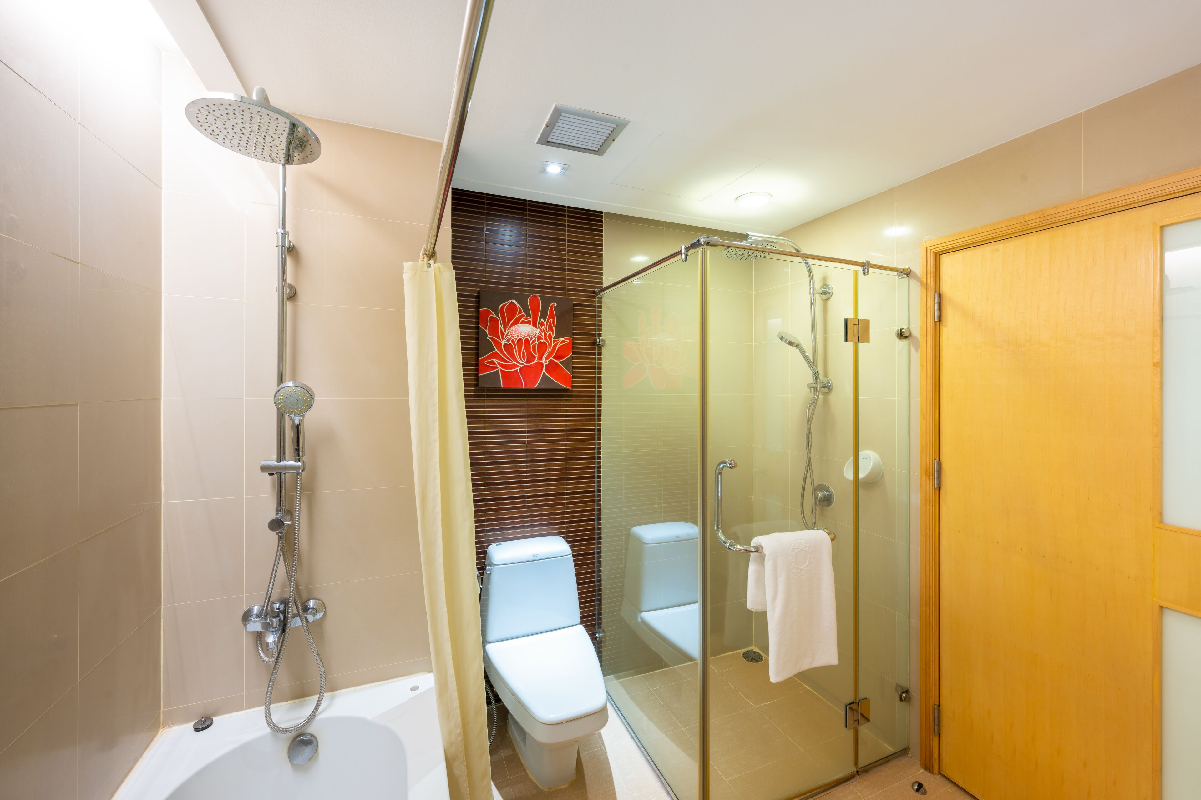 Een moderne badkamer met een glazen douchecabine, een badkuip en een toilet.