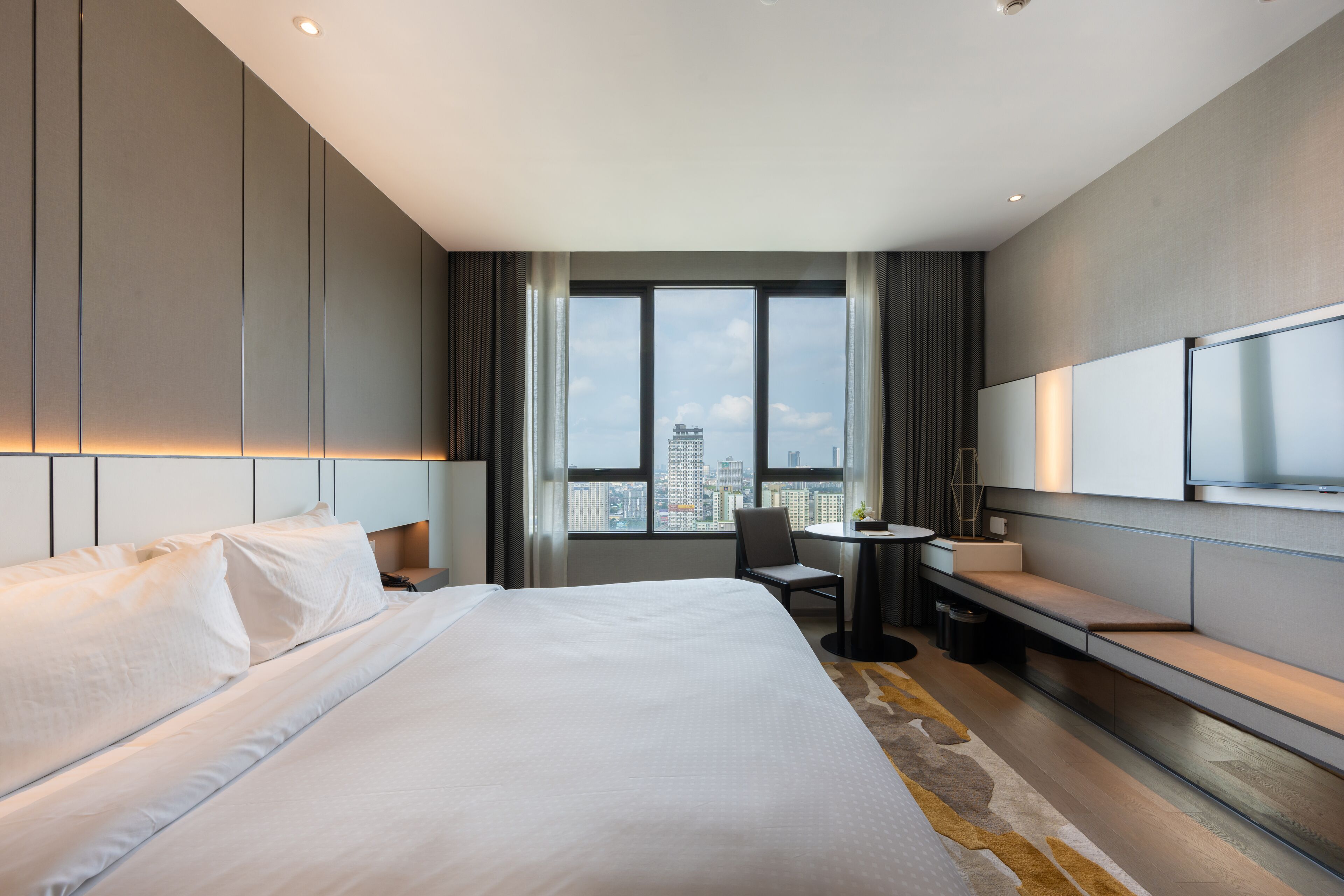 A modern hotel room with a large bed, a desk, and a TV.
