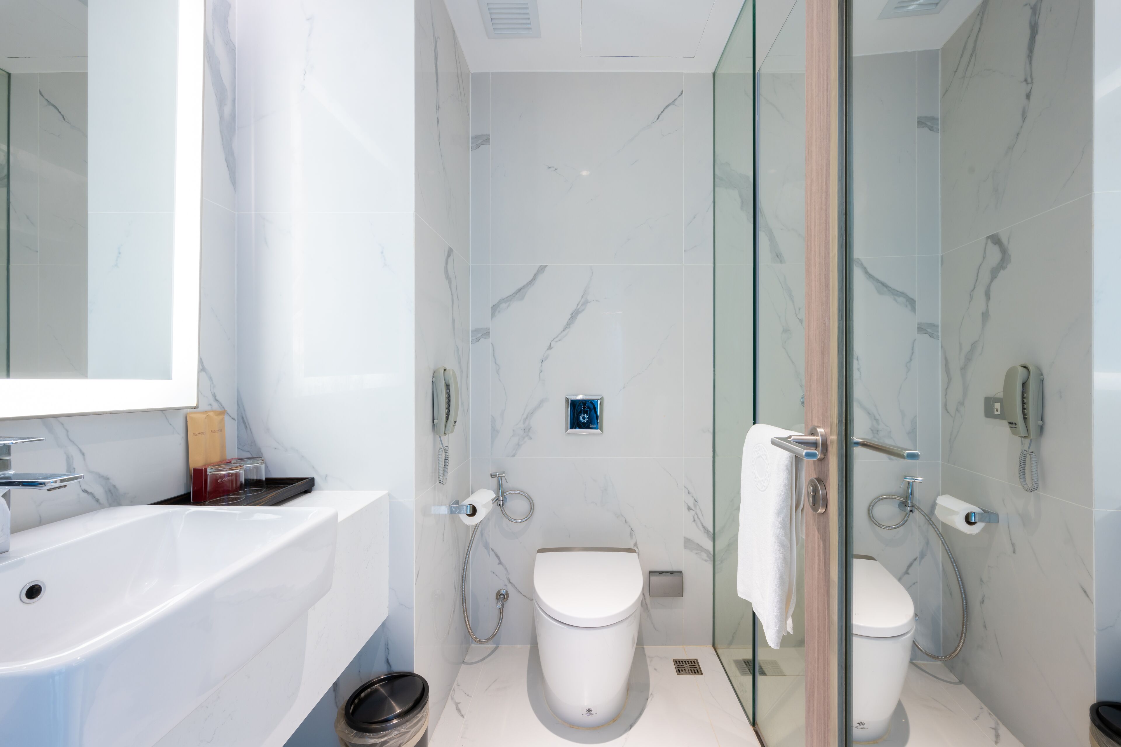 A modern bathroom with a glass shower enclosure, a white bathtub, and a separate toilet.