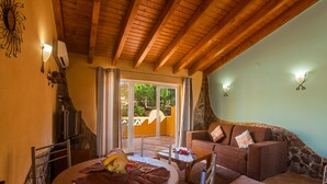 Una sala de estar acogedora con un muro de piedra decorativo, vigas de madera en el techo y una chimenea de piedra.