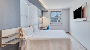 A modern hotel room with a bed, a desk, a chair, a TV, and a window with a city view. - One Ciudad de Mexico Patriotismo (Mexico City)