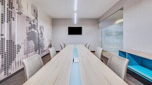A conference room with a long table, chairs, a TV screen, and a glass partition. - One Ciudad de Mexico Patriotismo (Mexico City)