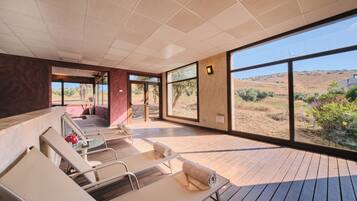 Un área de spa moderna con suelo de madera, ventanas amplias y vistas al paisaje desértico.