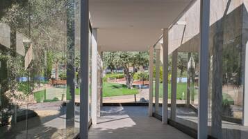 Un pasillo moderno con amplios ventanales y vistas a un jardín ajardinado.