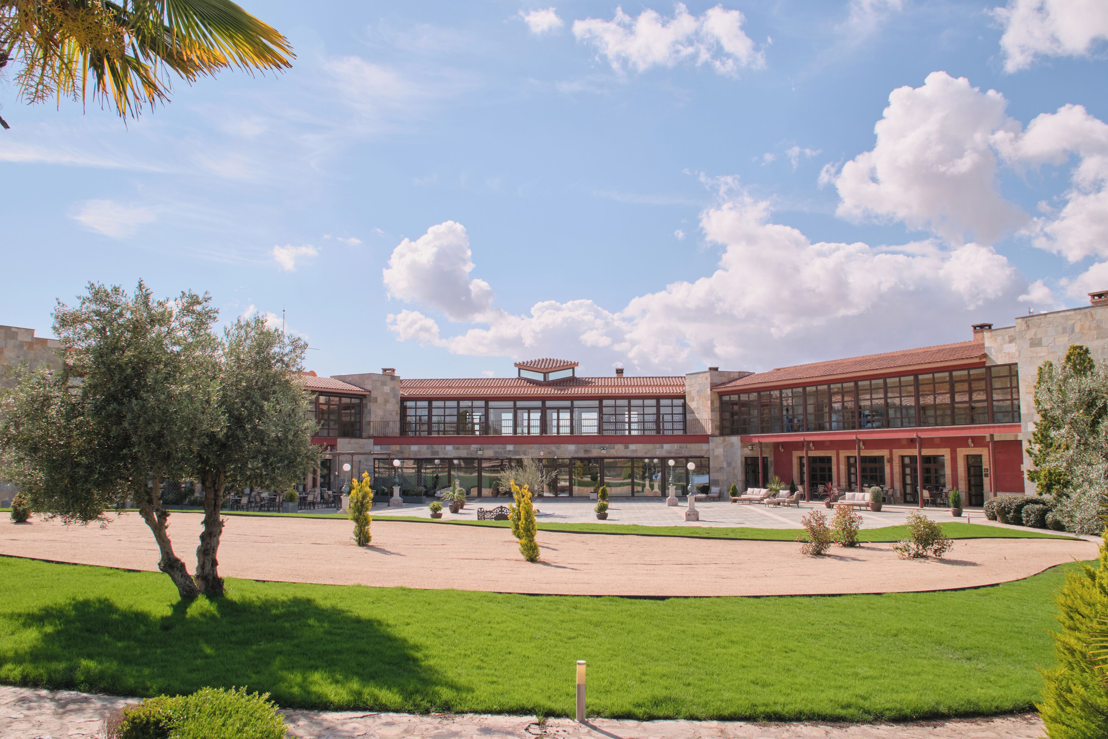 Ein Gebäude mit Innenhof, das moderne und traditionelle Architektur vereint und von gepflegter Bepflanzung umgeben ist.