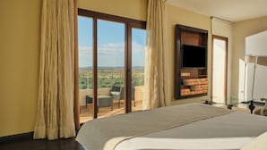 A hotel room with a large bed, a TV, and a balcony with a view of the countryside. - Hotel Spa Villa Nazules (Nambroca)