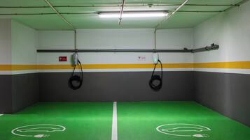 A parking garage with green and gray walls, yellow and gray stripes, and two electric vehicle charging stations.